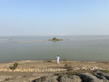 People looking at sea against clear sky