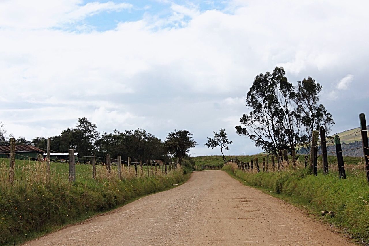 ROAD PASSING THROUGH FIELD AGAINST CLOUDY SKY