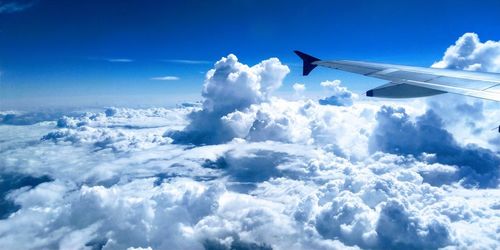 Airplane flying over cloudscape against blue sky