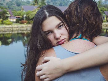 Portrait of sad daughter embracing mother while standing outdoors