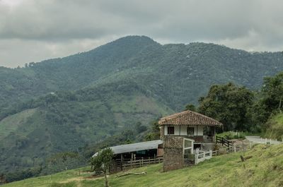 House amidst trees and mountains against sky