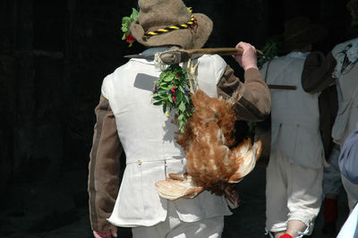 Rear view of man carrying chicken