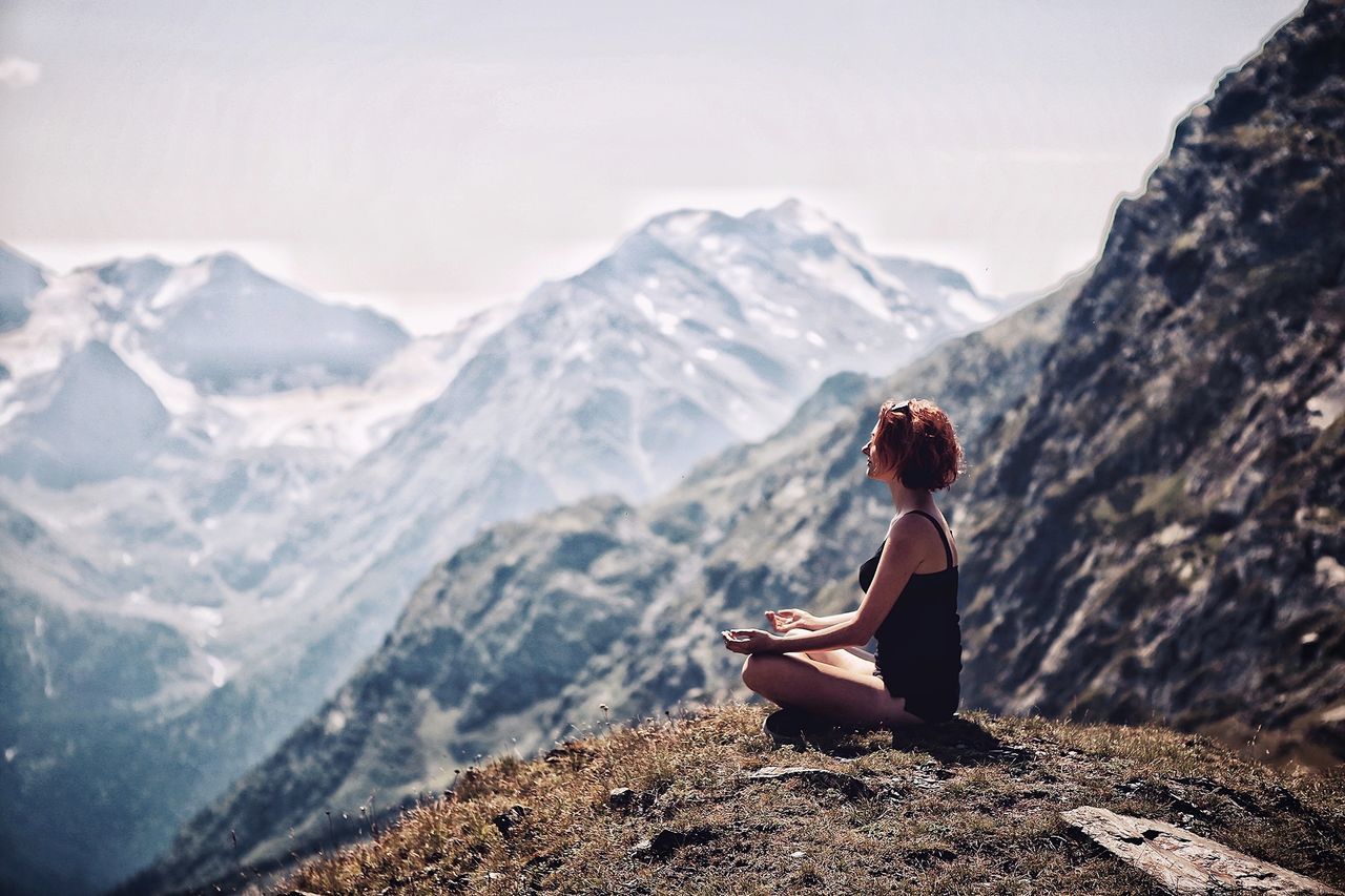 mountain, one person, leisure activity, real people, scenics - nature, beauty in nature, lifestyles, sitting, rock, rock - object, mountain range, solid, tranquility, nature, non-urban scene, young adult, tranquil scene, day, women, outdoors