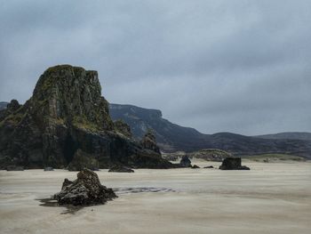 Scenic view of rocks on shore against sky