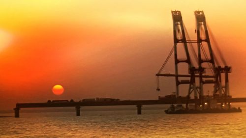 Silhouette pier over sea against sky during sunset