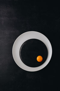 Directly above shot of orange tea on table against black background