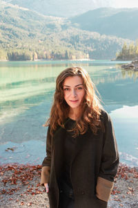 Portrait of young woman looking away against lake