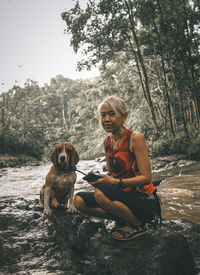 Portrait of woman sitting on rock by lake