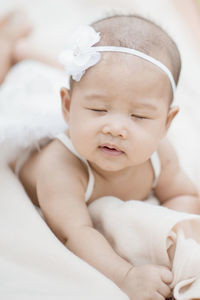 Close-up of cute baby girl wearing headband while lying on blanket