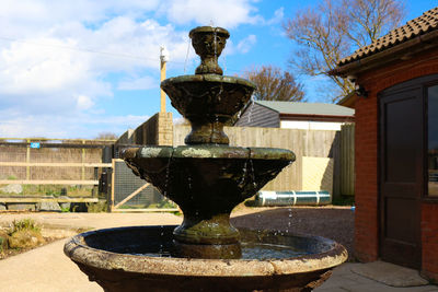 Fountain by house against sky