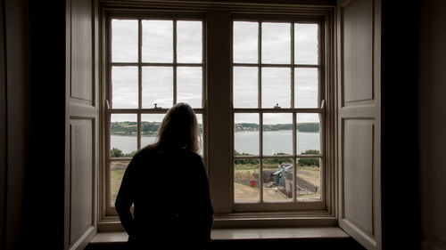 Rear view of woman looking through window