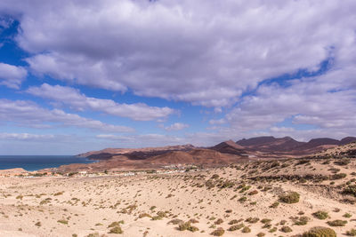 Scenic view of desert against cloudy sky