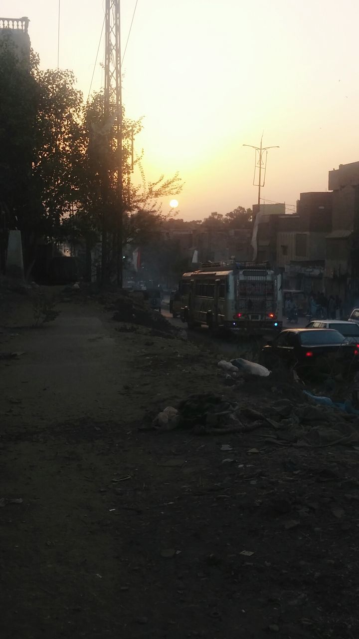 sunset, transportation, building exterior, built structure, mode of transport, architecture, street, car, sky, clear sky, city, land vehicle, electricity pylon, road, outdoors, orange color, power line, sunlight, no people, house