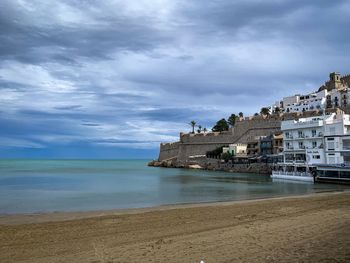 Scenic view of beach by buildings against sky