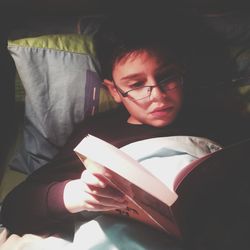 Close-up of young man reading book at home