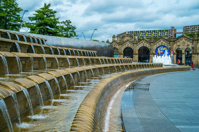 View of swimming pool in city against cloudy sky
