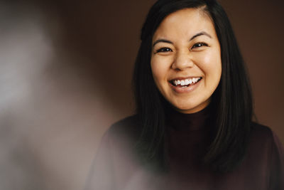 Portrait of cheerful woman against brown background