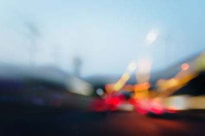 Defocused image of illuminated road against sky