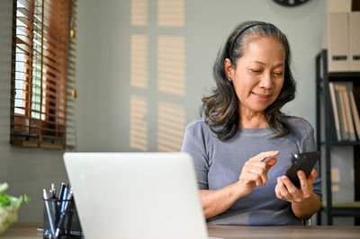Portrait of young woman using laptop at home