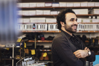 Happy confident male looking away while standing in shoe repair store