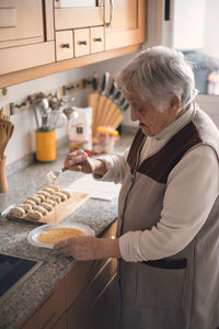 High angle view of senior woman preparing food on kitchen counter