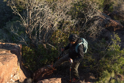 Middle-aged man climbs the mountain in the garraf natural park, supported by hiking poles.