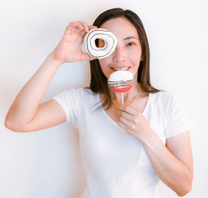 Portrait of smiling woman holding sweet food over white background