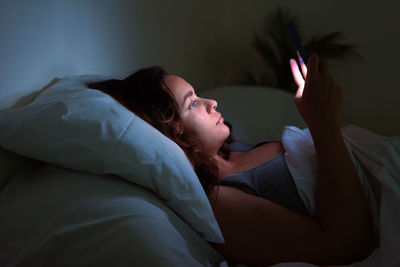 Side view of woman lying on bed at home