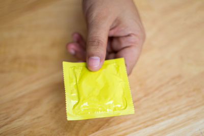 Close-up of man holding condom on table