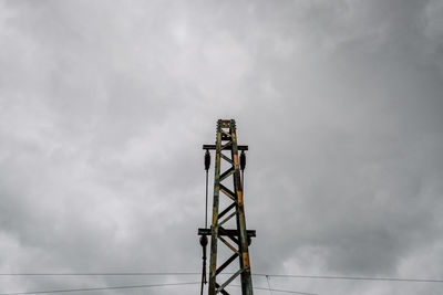 Low angle view of communications tower against cloudy sky