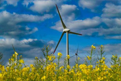 Wind turbines on field against sky