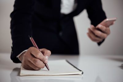 Midsection of man using mobile phone on table