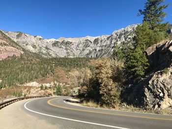 Road by mountains against clear sky