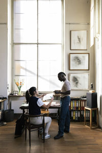 Multiracial male and female colleagues discussing over document in workshop