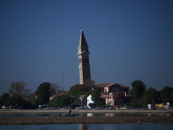 Tower amidst buildings against clear blue sky