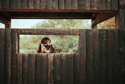 Portrait of woman photographing through fence