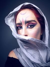 Close-up portrait of young woman with make-up over black background