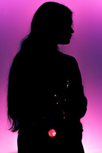 Portrait of silhouette woman standing against pink background