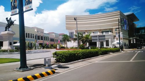 Road by buildings against sky in city
