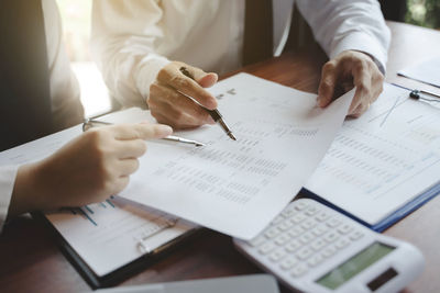 Midsection of man holding paper with text on table