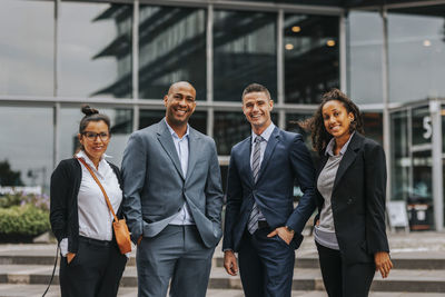 Portrait of smiling multiracial male and female business professionals standing in front of building