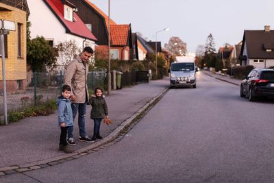 Father standing with children on sidewalk during autumn