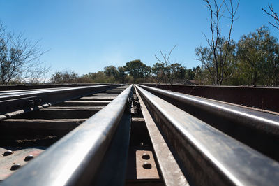 Surface level of railroad tracks against clear blue sky