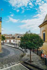 Street amidst buildings in town against sky