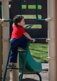 Little toddler climbing up stairs on a slide at a park