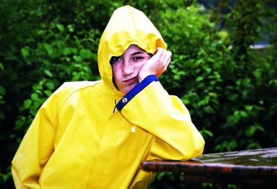 Portrait of woman wearing yellow raincoat against plants