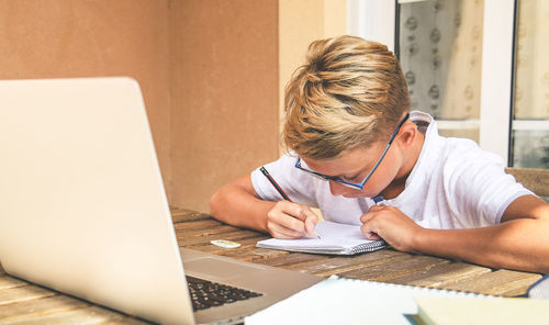 Student doing homework. boy writing, drawing sitting at the table. school, youth, education concept.