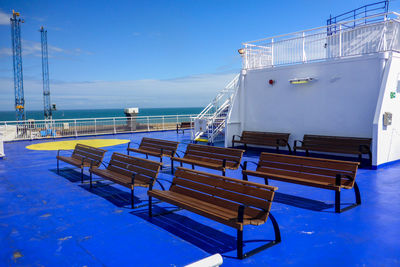 Benches arranged on boat deck at ship against sky