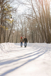 Rear view of women walking on snow covered land