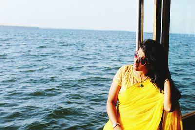 Woman sitting on ferry boat by sea against sky